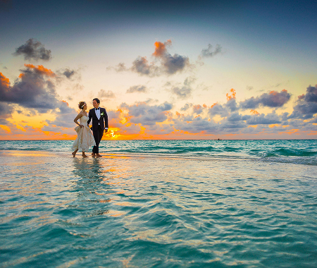 Couple walking in the shallows at sunset on a Maui beach