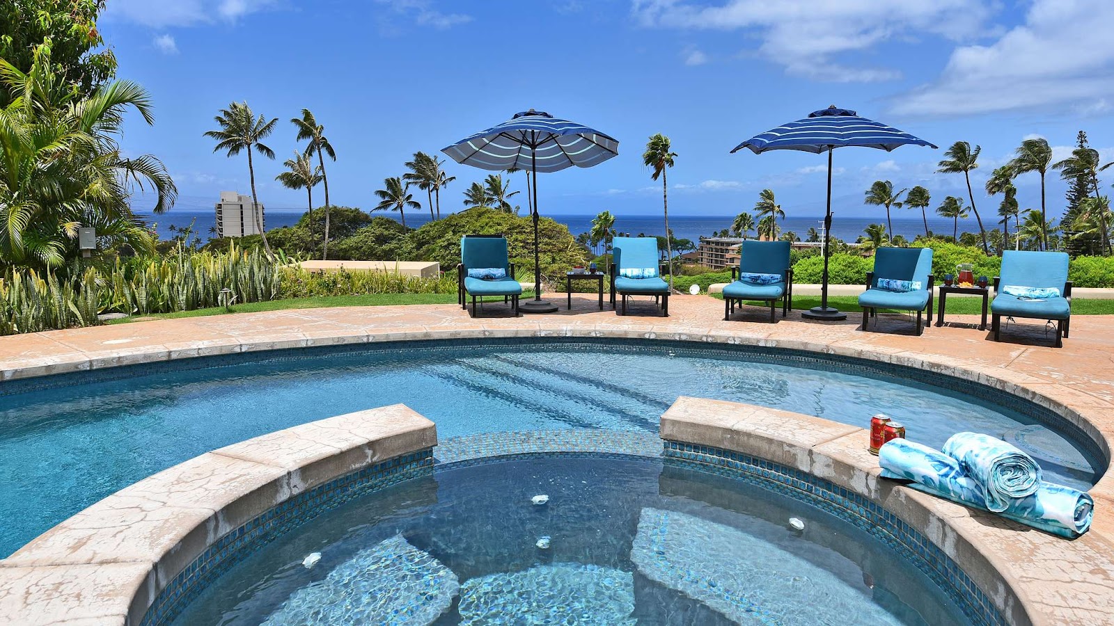 Resort pool and hot tub with lounge chairs and an ocean view at a Maui vacation rental