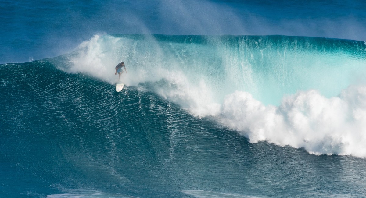 Professional big wave surfer riding massive 40-foot wave at Pe'ahi Jaws surf break on Maui's north shore