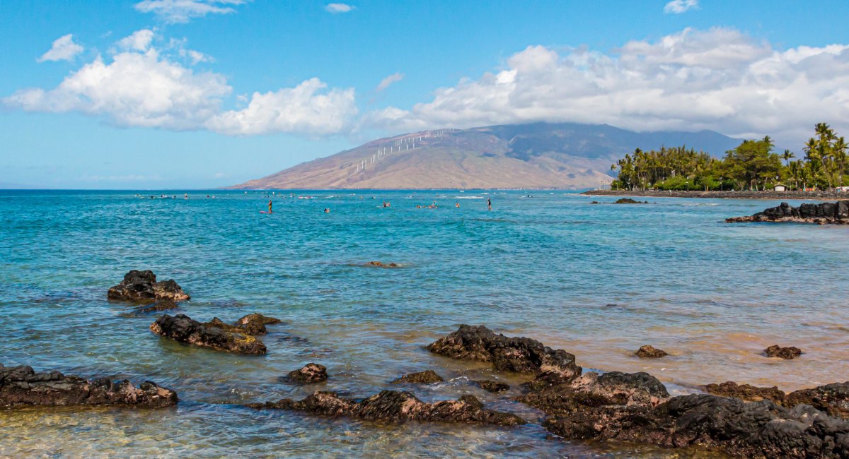 Beginner surfers learning at The Cove Kalama Beach Park Kihei with calm turquoise waters and West Maui Mountains backdrop